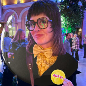Artist Sadie Lee showing off a badge saying Arty!