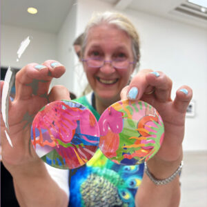 A smiling participant at the Saatchi Gallery showing off two colourful badges