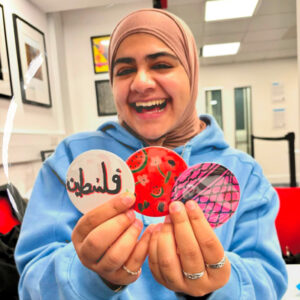 A smiling participant at Soho Poly showing off her badges