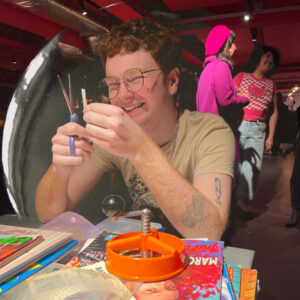 Dev smiling while making a collage at the badge table
