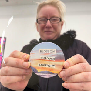 A participant holding a badge saying Blossom Through Adversity