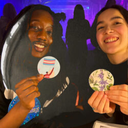 Two smiling participants holding badges they made