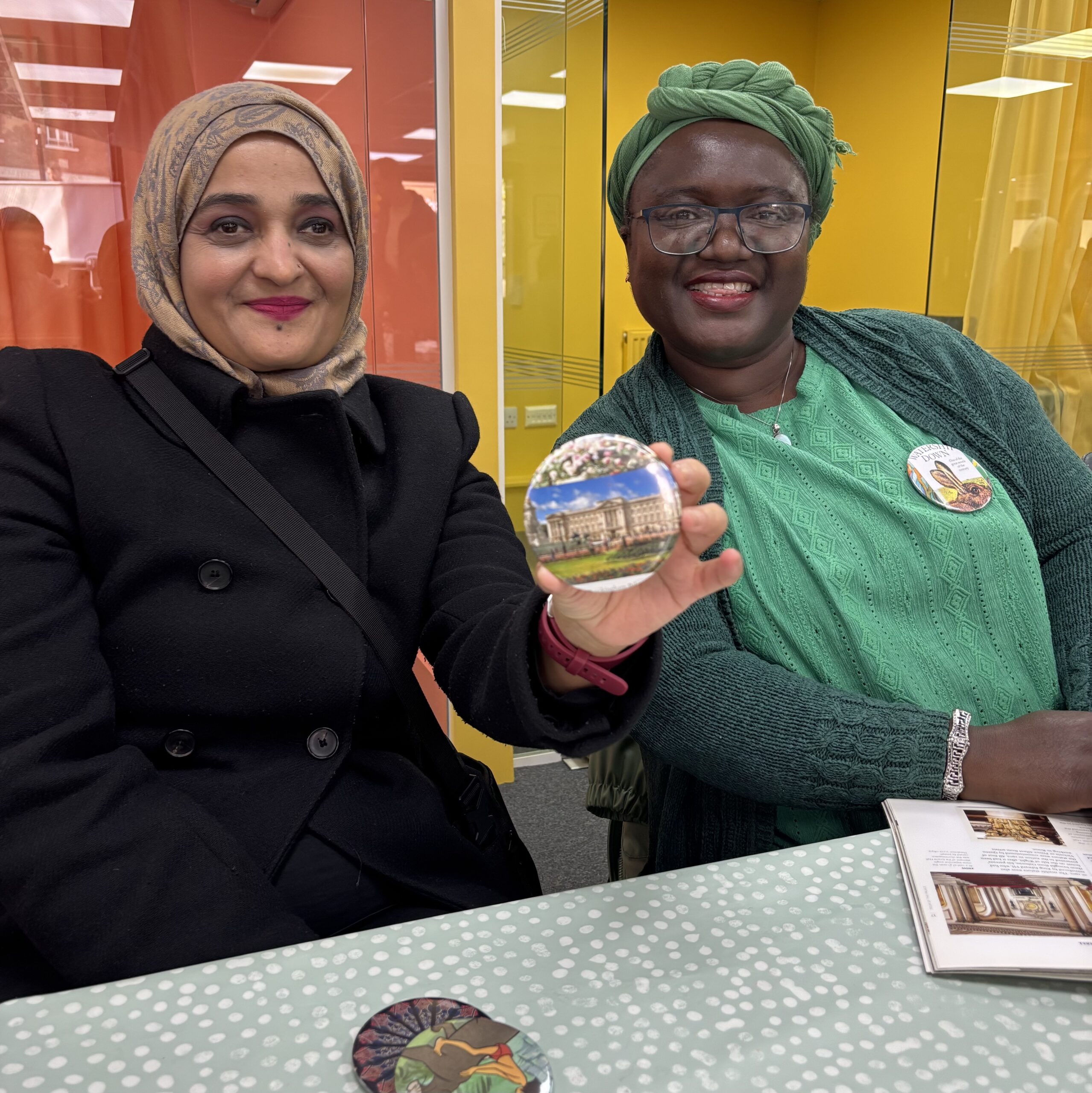 Two smiling participants at Rampayne St Community Hub showing off their badges